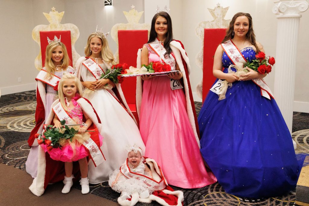 photo of pageant winners wearing formal gowns and holding bouquets of roses.